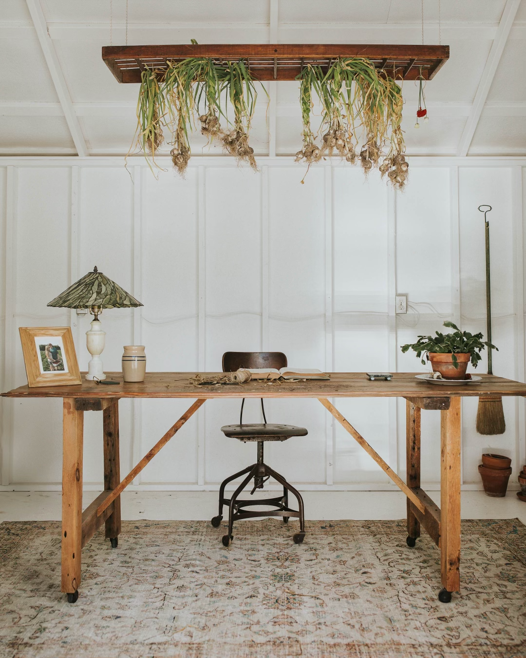 garlic braids hanging from a suspended wooden rack in a garden shed over a desk