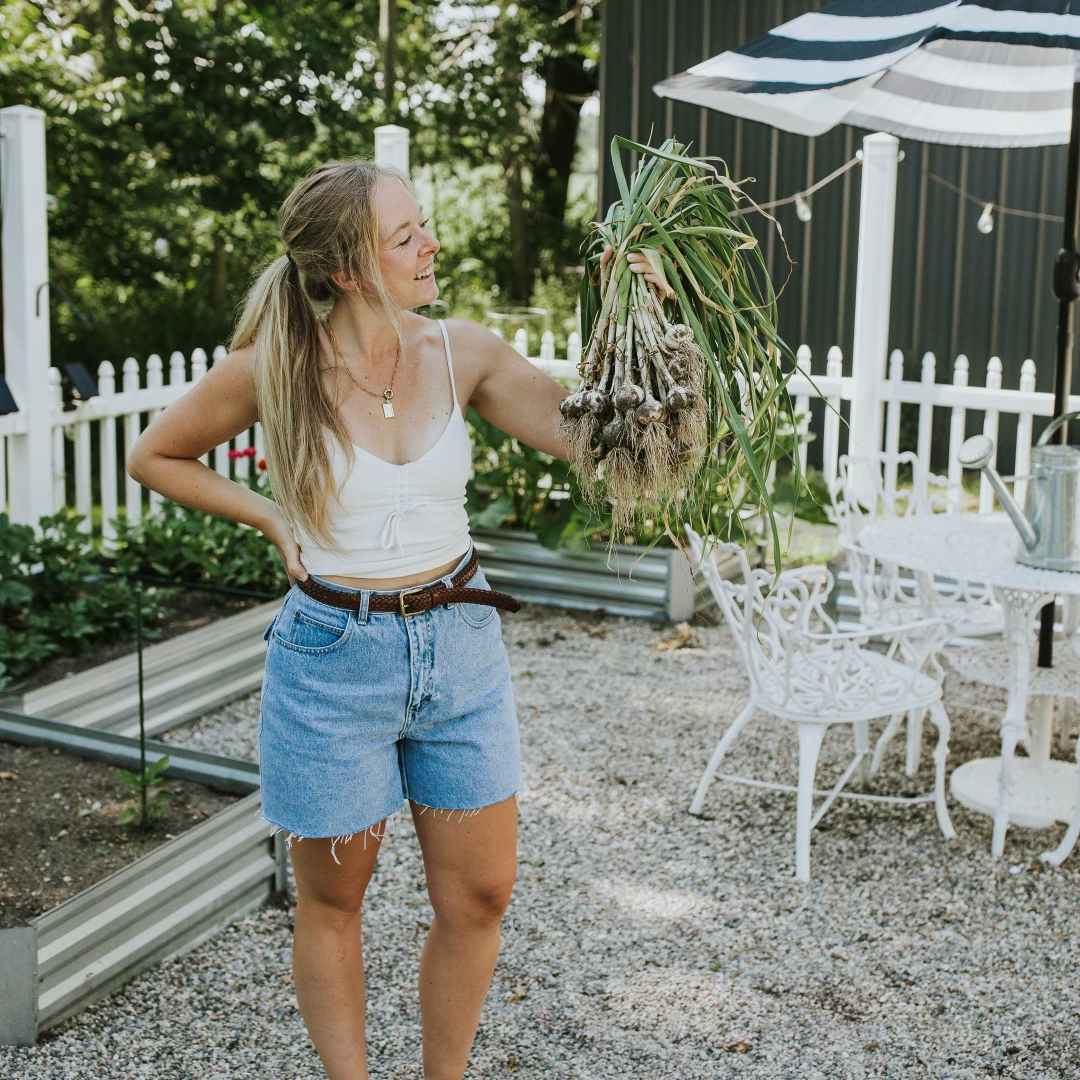 smiling woman holding a bunch of garlic